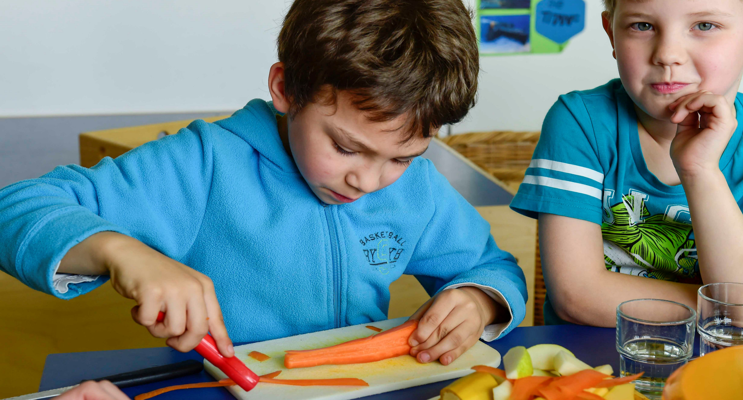 Zwei Kinder im Schulalter beim Schälen von Möhren