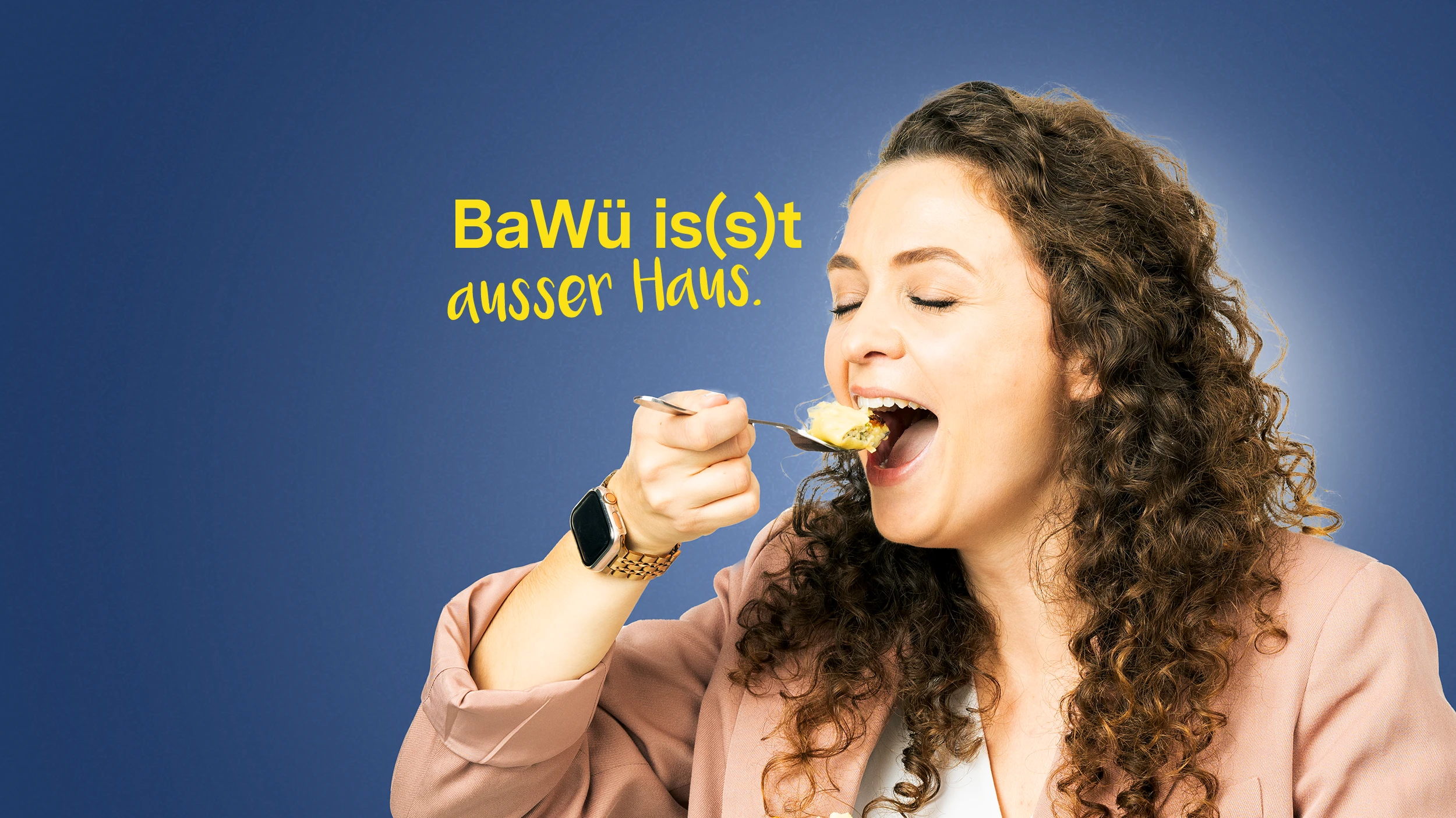 BaWü is(s)t außer Haus. Eine Frau führt bei geschlossenen Augen eine Gabel mit einer Maultasche zum Mund.