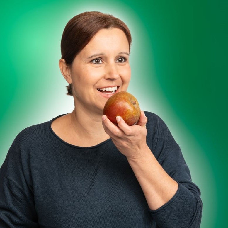 Eine junge Frau beißt herzhaft in einen Apfel