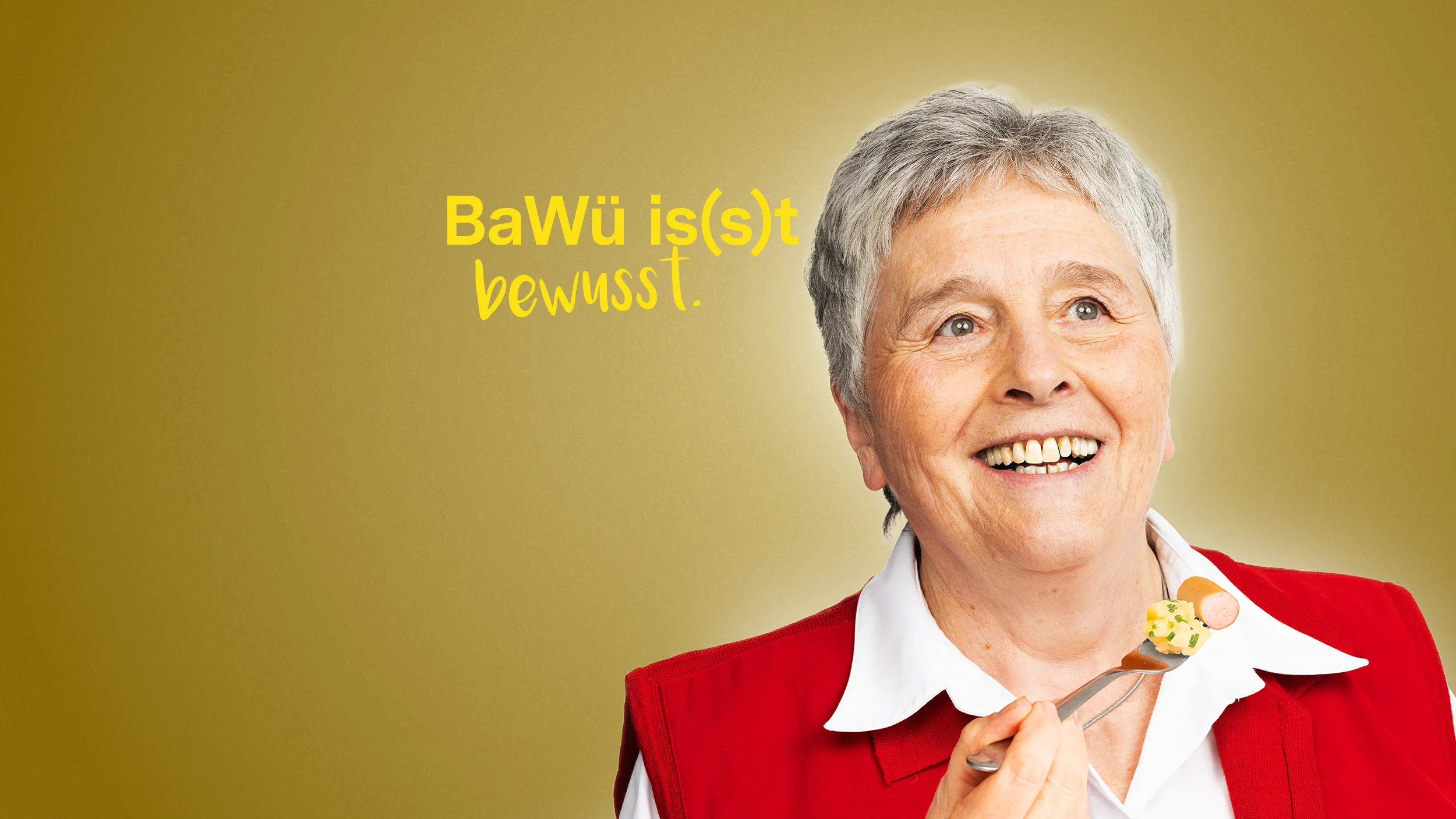 BaWü is(s)t bewusst. Eine ältere Frau lächelt und hält eine Gabel in der Hand, auf der etwas Kartoffelsalat und ein Stück Saitenwurst zu sehen ist.