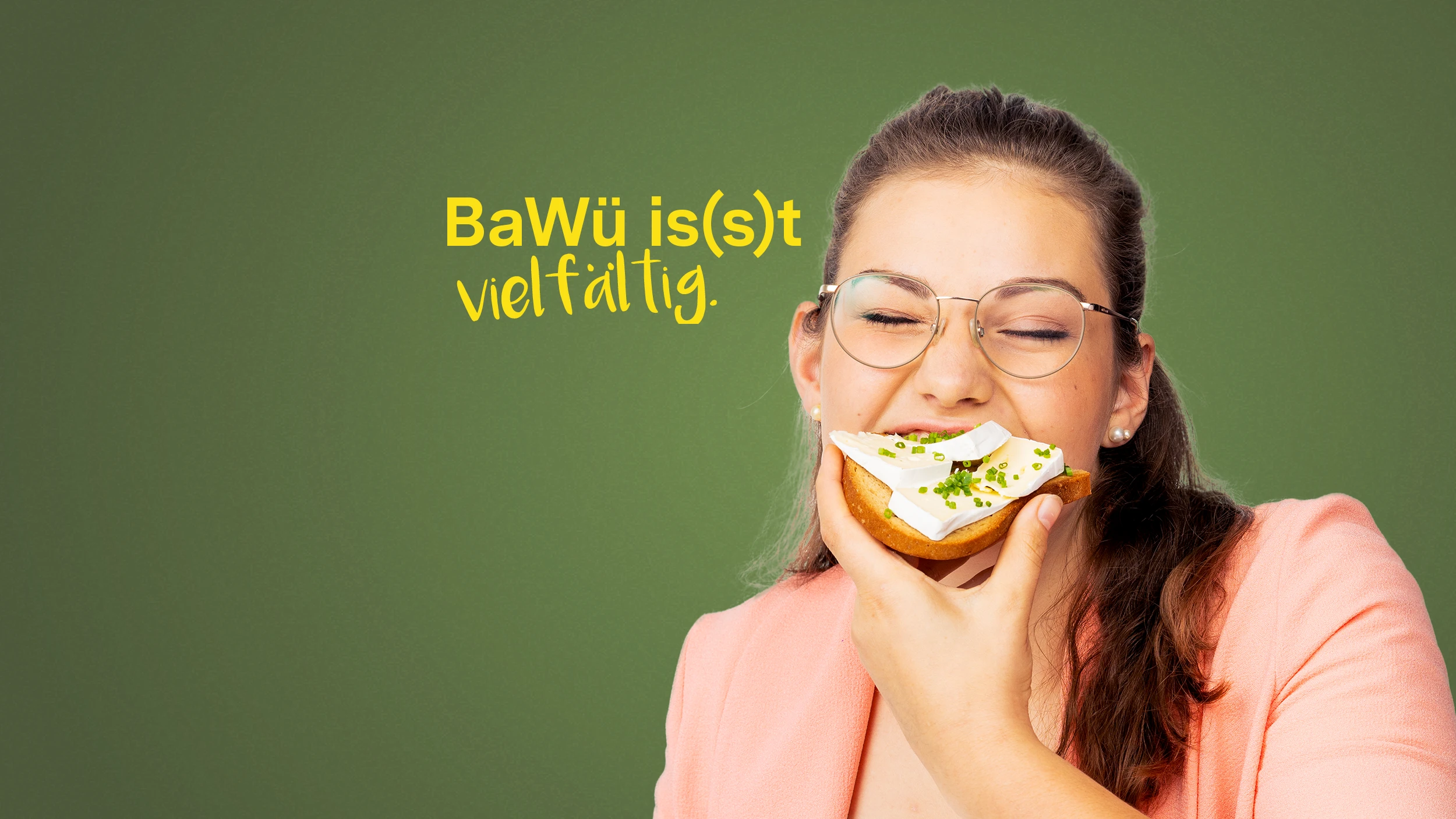BaWü is(s)t vielfältig. Eine junge Frau beißt herzhaft in eine Brotscheibe, die mit Käse belegt ist.