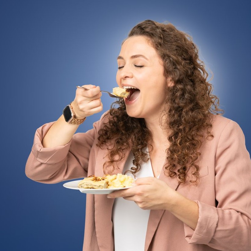 Eine Frau ist mit Genuss Maultauschen.